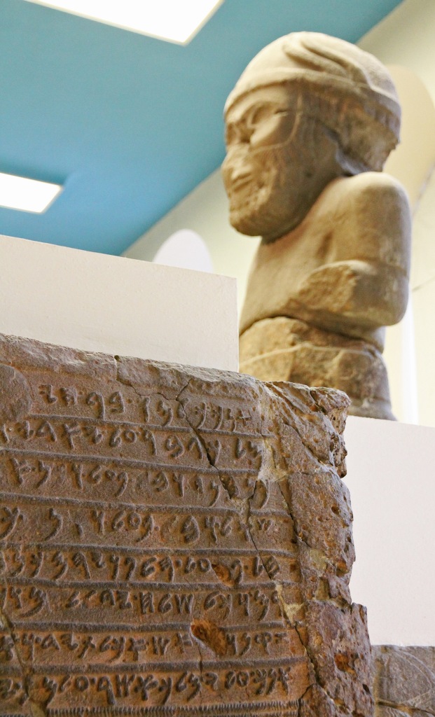 Tablet with inscription. Background: a colossal statue of the Weather God Hadad.